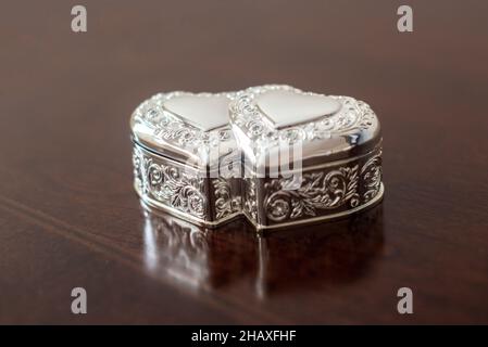 Cassa ad anello a forma di cuore doppia ornata in argento su tavola in legno Foto Stock