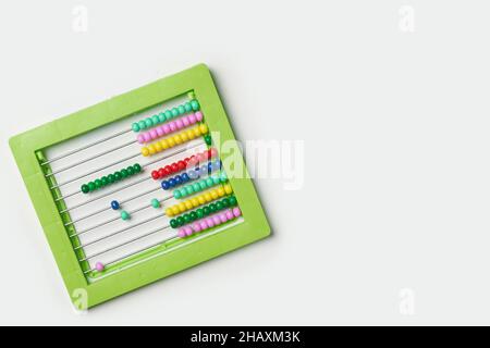 Calcolatrice a perle colorate su bianco. Contatore manuale di sfere in plastica verde per matematica. Abaco colorato con perline. Istruzione scolastica, calcolatrice per prescolare Foto Stock
