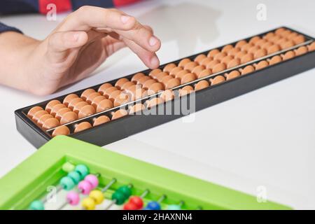 Fare matematica mentale o aritmetica mentale. Mano di ragazzino che usa abaco per calcolare. Imparare ad usare abacus nei corsi di matematica mentale. Un bambino che fa Foto Stock