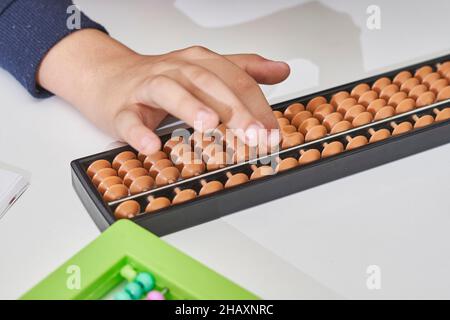 Fare matematica mentale o aritmetica mentale. Mano di ragazzino che usa abaco per calcolare. Imparare ad usare abacus nei corsi di matematica mentale. Un bambino che fa Foto Stock