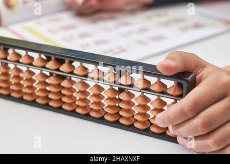 Fare matematica mentale o aritmetica mentale. Mano di ragazzino che usa abaco per calcolare. Imparare ad usare abacus nei corsi di matematica mentale. Un bambino che fa Foto Stock