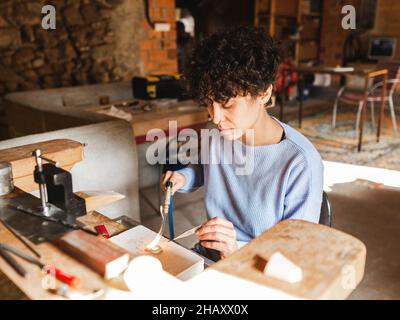 Da sopra di oreficeria e artigiano femminile etnico utilizzando torcia a gas per la saldatura di particolari di anello Foto Stock