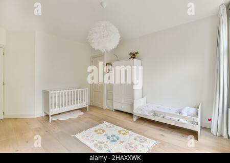 Spaziosa camera da letto della bambina. Pavimento in legno con tappeti,  culla di bianco e decorazioni colorate Foto stock - Alamy