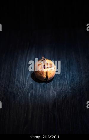Vista dall'alto di melograno mezzo pelato e soprammaturo posto su sfondo scuro Foto Stock