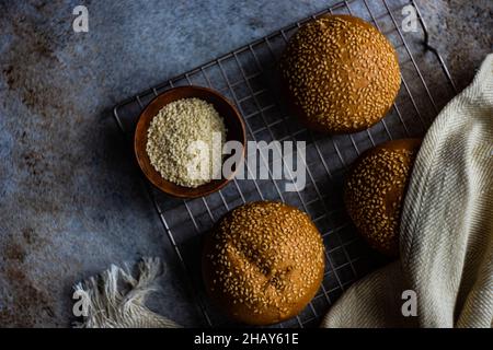 Panini fatti in casa con semi di sesamo su una griglia di raffreddamento Foto Stock