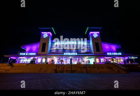 Felixstowe, Suffolk, Regno Unito: L'ingresso al molo di Felixstowe di notte illuminato da luci viola. Foto Stock