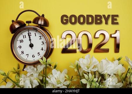 Arrivederci 2021 testo con alarmclock e decorazione floreale su sfondo giallo Foto Stock