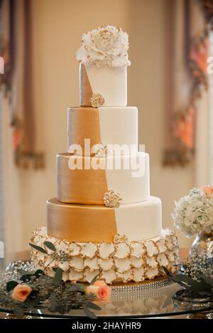 Splendida torta nuziale a cinque piani in oro e bianco al ricevimento nuziale Foto Stock