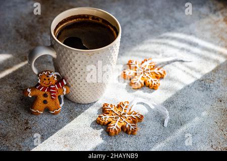 Tazza di caffè nero, fiocchi di neve e pan di zenzero uomini biscotti di Natale su un tavolo Foto Stock