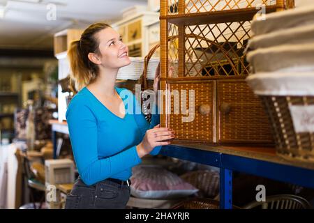 Giovane donna consumatore vicino vimini commode Foto Stock