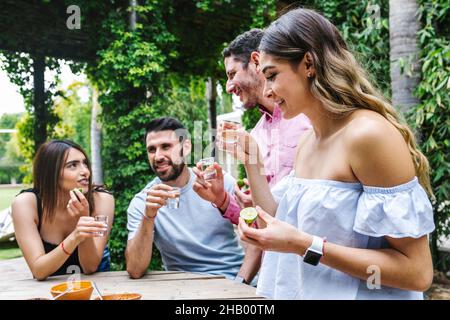 Colpo di tequila. Gruppo di giovani amici latini che si incontrano per tequila shot o mezcal bevande facendo un brindisi nella terrazza del ristorante in Messico America Latina Foto Stock