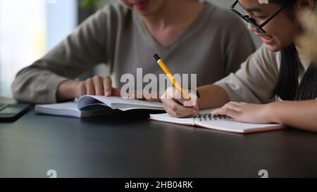 Corto girato insegnante giovane femmina che aiuta la bambina che fa i compiti. Foto Stock