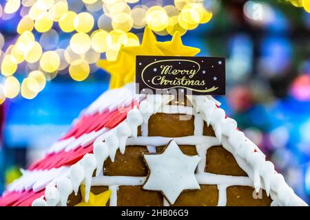 Casa del pane di zenzero con saluto di Natale allegro e bokeh sfondo. Foto Stock