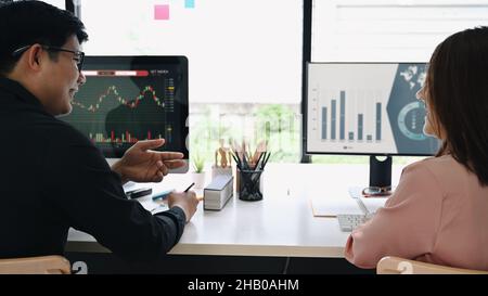 Gruppo di visualizzazione posteriore del commerciante di stock che controlla e analizza il grafico finanziario sul calcolatore insieme in ufficio. Foto Stock