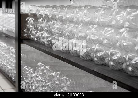 Le bottiglie di plastica vuote vengono impilate in file sugli scaffali del magazzino. Messa a fuoco selettiva Foto Stock