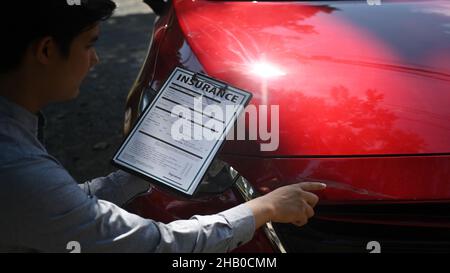 Cropped agente di assicurazione del colpo che esamina l'automobile dopo l'incidente. Foto Stock