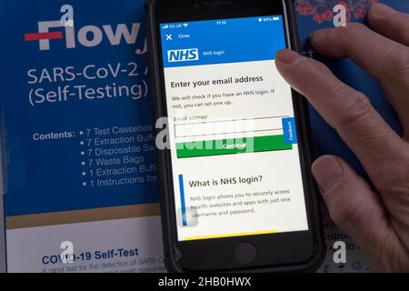 Man consente di aprire la schermata di accesso dell'app NHS per immettere l'indirizzo e-mail per l'accesso e segnalare il risultato del test del flusso laterale Foto Stock