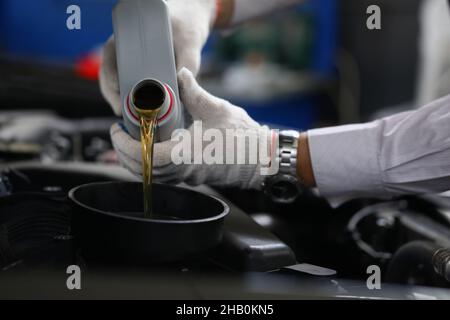 L'operatore effettua il rifornimento e versa olio nuovo nell'automobile del motore Foto Stock