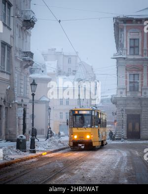 Tram giallo sulla piazza centrale del mercato in inverno Lviv città, Ucraina, Europa. Paesaggio urbano mattutino Foto Stock