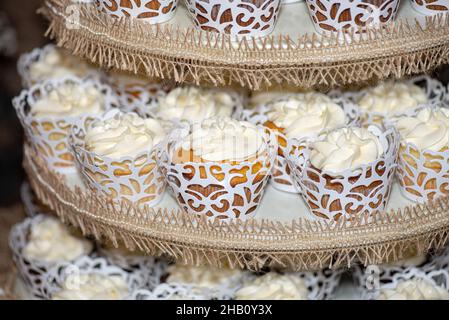 La torre dei cupcake glassati alla vaniglia al bar dessert durante il matrimonio Foto Stock