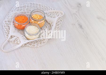 Grani in vasetti di vetro su sfondo di legno. Prodotti biologici alla rinfusa e cereali in un negozio di rifiuti zero. Stile di vita a basso contenuto di rifiuti. Shopping ecologico nel negozio di alimentari Foto Stock