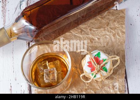 Un bicchiere di whiskey sul ghiaccio accanto ai biscotti al burro e una bottiglia di whiskey. Foto Stock