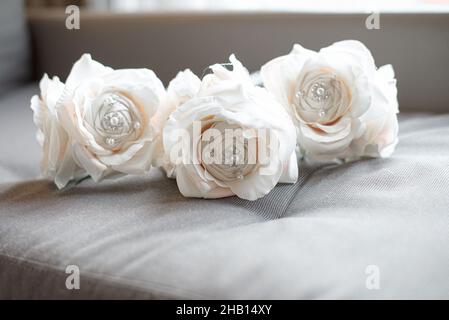 Tre fiori di seta bianca su cuscino beige Foto Stock