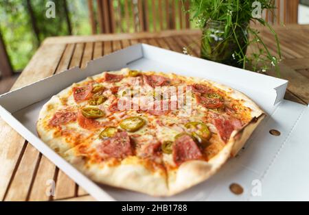 Pizza calda croccante con prosciutto, peperoni e jalapeno. Foto Stock