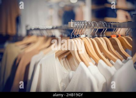 Appendiabiti sulla rotaia del negozio. Shopping in negozio. Vestiti su appendiabiti in negozio per la vendita. Sfocatura dello sfondo. Abiti alla moda in un bouti Foto Stock