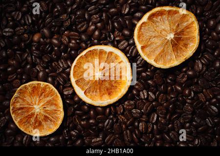 Più fette di arancia essiccate su fondo di chicchi di caffè torrefatto intero. Nuova ricetta per bevande fantasiose Foto Stock