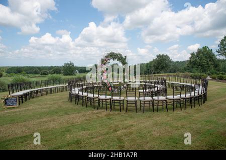 Unica cerimonia nuziale con motivo a spirale, ambientata nella campagna delle colline ondulate, con sedie chiavari marroni e cuscini bianchi Foto Stock