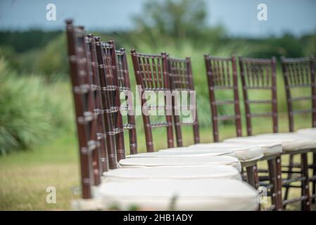 Unica cerimonia nuziale con motivo a spirale, ambientata nella campagna delle colline ondulate, con sedie chiavari marroni e cuscini bianchi Foto Stock