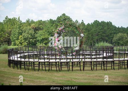 Unica cerimonia nuziale con motivo a spirale, ambientata nella campagna delle colline ondulate, con sedie chiavari marroni e cuscini bianchi Foto Stock