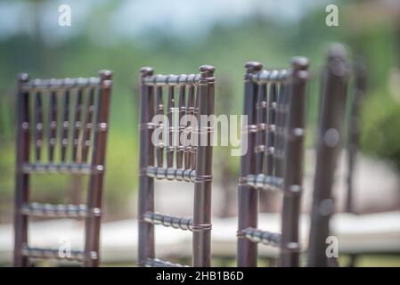 Unica cerimonia nuziale con motivo a spirale, ambientata nella campagna delle colline ondulate, con sedie chiavari marroni e cuscini bianchi Foto Stock