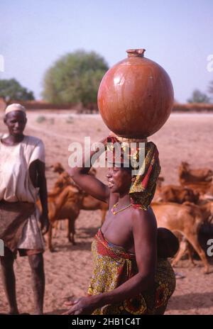 Vita nella regione Sahel della Nigeria settentrionale, Africa occidentale, all'inizio del 1980s - donna che trasporta l'acqua Foto Stock