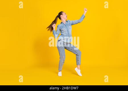 Foto a tutta lunghezza di funky adorabile giovane donna vestito jeans camicia danzante sorridente isolato colore sfondo giallo Foto Stock