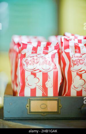 Molte file di popcorn in sacchi di carta bianca con strisce verticali rosse e le parole 'fresco popcorn' stampate sui sacchetti Foto Stock