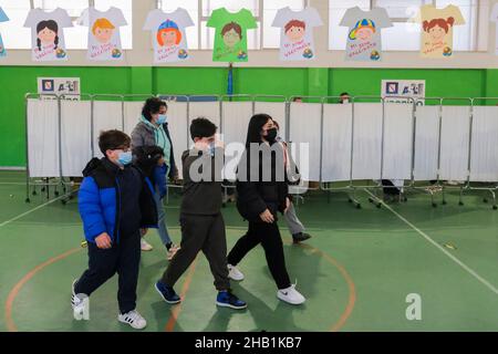 Bambini con le loro madri all'uscita del centro di vaccinazione istituito nella scuola di ginnastica Vittorino da Feltre a San Giovanni a Teduccio, un sobborgo ad est di Napoli, nel sud Italia, il 16 dicembre 2021. La somministrazione del vaccino pediatrico COVID-19 mRNA Comirnaty (Pfizer) a bambini di età compresa tra 5-11 e 24 anni ha iniziato oggi a proteggere la loro salute e a limitare l'avanzamento del virus. Foto Stock