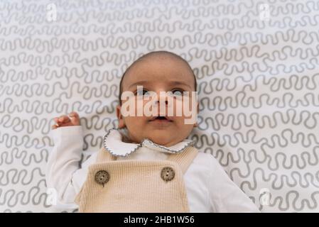 Bambino elegante in vestito e salopette sdraiati sul letto. Foto Stock