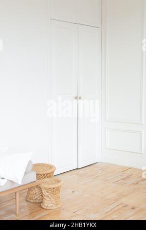 Porta bianca con pavimento in legno e sedie in vimini Foto Stock