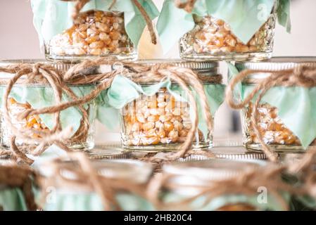 I chicchi di popcorn sono impilati in vasetti di vetro con cime verdi al dessert bar Foto Stock