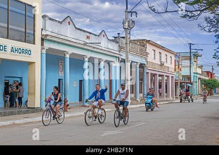 I cubani in bicicletta attraverso la strada con edifici colorati nella città Ciego de Ávila sull'isola Cuba, Caraibi Foto Stock