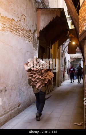 Fez, Marocco - Febbraio 23. 2019: Gente locale che trasporta la pelle grezza sul retro attraverso la stretta corsia in medina (centro storico) al mercato vicino a. Foto Stock