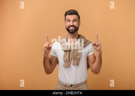WOW, cerca. Ritratto di uomo stupito che punta fino a posto vuoto su sfondo arancione, esprimendo sorpresa con ampio sorriso aperto e mostrando spazio copia per la pubblicità Foto Stock