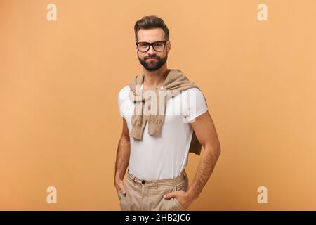Ritratto di felice sorridente bell'uomo porteggiato con maglietta bianca che posa su sfondo arancione. Foto studio. Foto di scorta Foto Stock