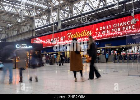 La gente alla stazione ferroviaria di Waterloo, Londra Regno Unito in dicembre - viaggiatori a lunga esposizione che precipitano il concetto di hurrying Foto Stock