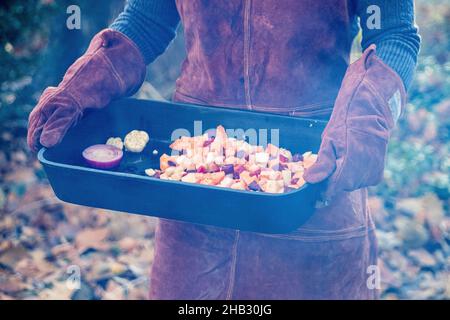 Persona che trasporta una padella di verdure tostate all'aperto Foto Stock