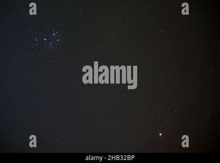 Pleiades (conosciuto anche come Seven Sisters) open star cluster sul cielo notturno invernale, luminoso pianeta rosso Marte in basso a destra, foto a lunga esposizione Foto Stock