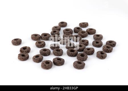 un mucchio di anelli neri di cereali isolati su sfondo bianco, deliziosi e utili anelli colazione cereali, vista laterale primo piano Foto Stock