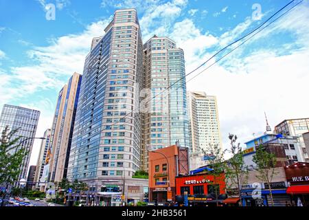 Alti edifici nel centro di Seoul in Corea del Sud con una strada e diversi negozi in primo piano. Foto Stock